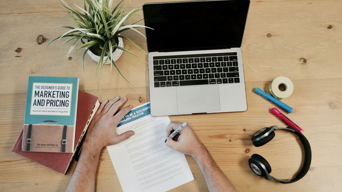 Skrivbord med anteckningar, laptop och en bok om marknadsföring och prissättning